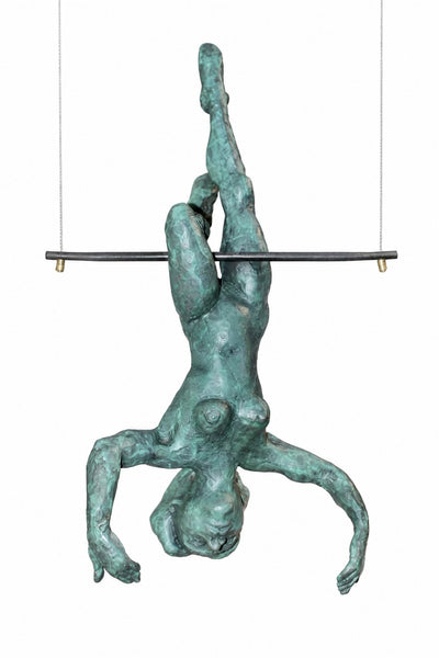 A hanging sculpture of a human figure suspended upside down from a horizontal bar, with a textured green patina finish, shown against a plain white background.