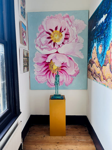 Peonies by Stephanie Fuller displayed at the end of a hallway, behind a green figure sculpture on a yellow plinth.