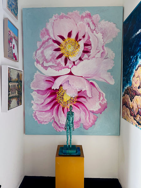 Closer view of Stephanie Fuller’s Peonies painting, with two oversized pink flowers behind a green figure sculpture.