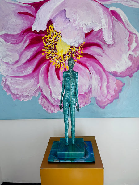Detail of a pink peony’s textured petals and yellow centre, with a green figure sculpture in front of the painting.